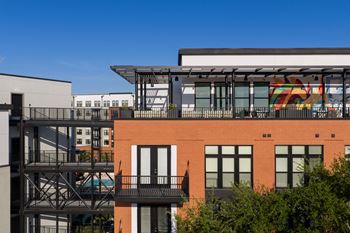 A red brick building with a balcony and a mural on the side